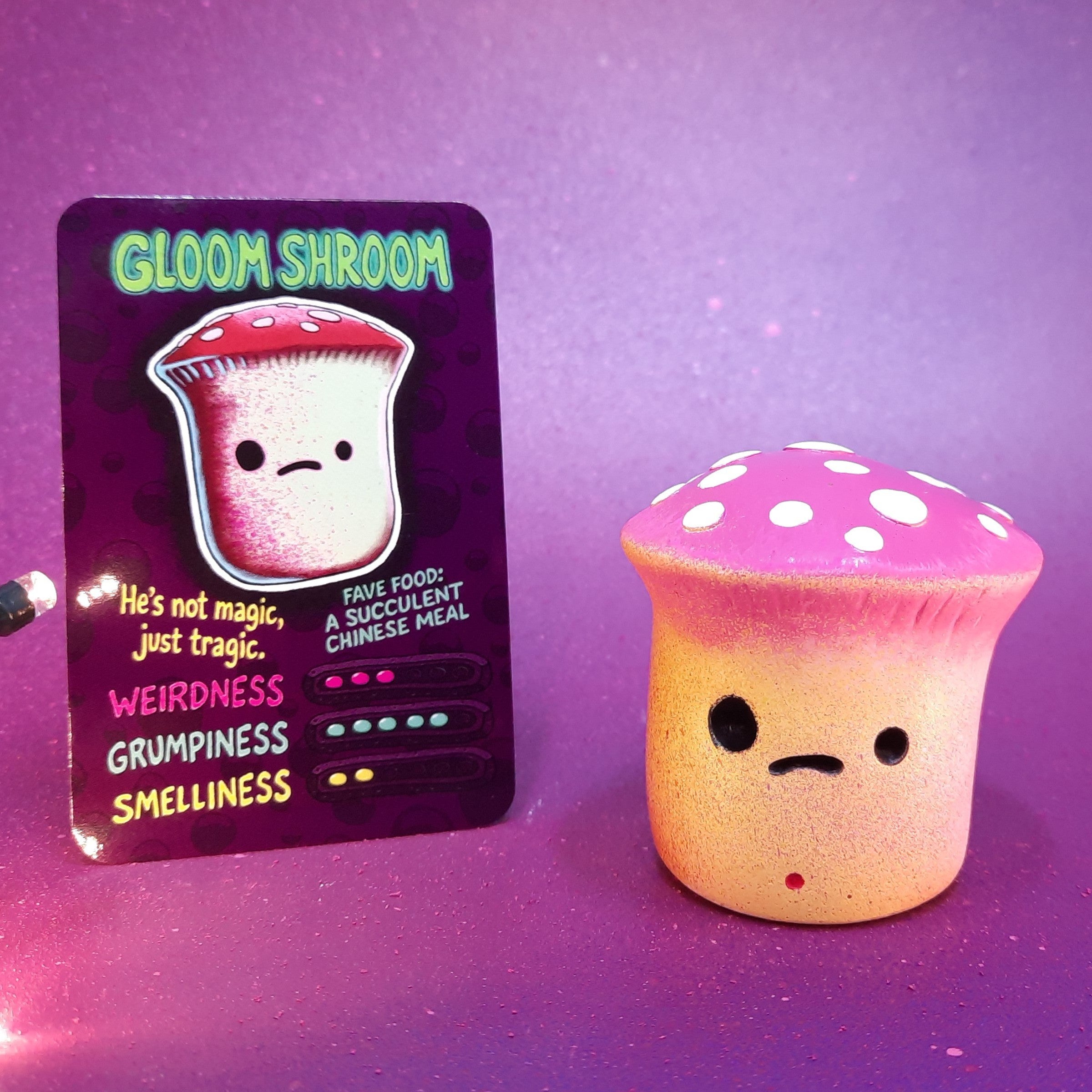 Gloom Shroom  mushroom character with a card on a purple background