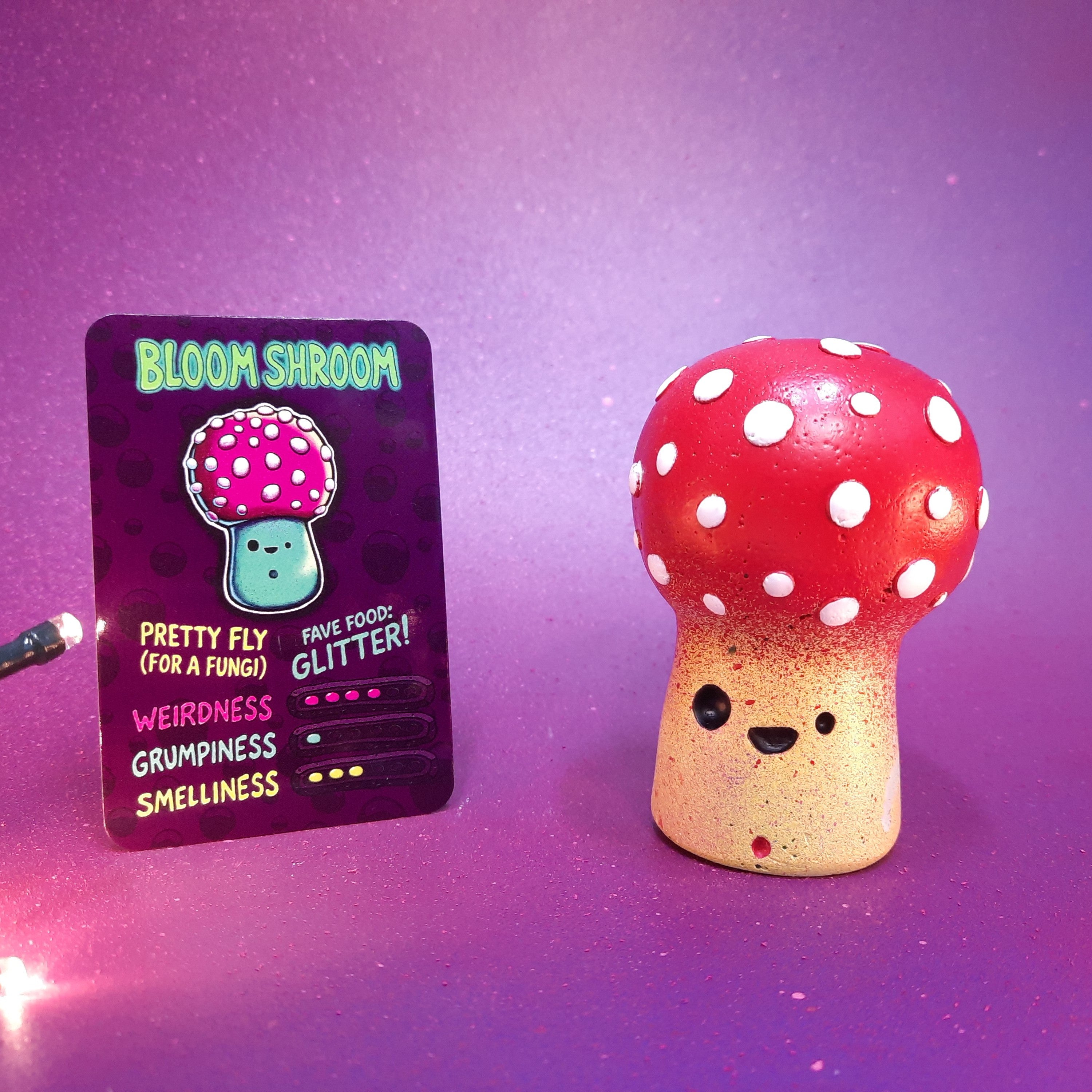 Mushroom figurine with a card labeled 'Bloom Shroom' on a purple background