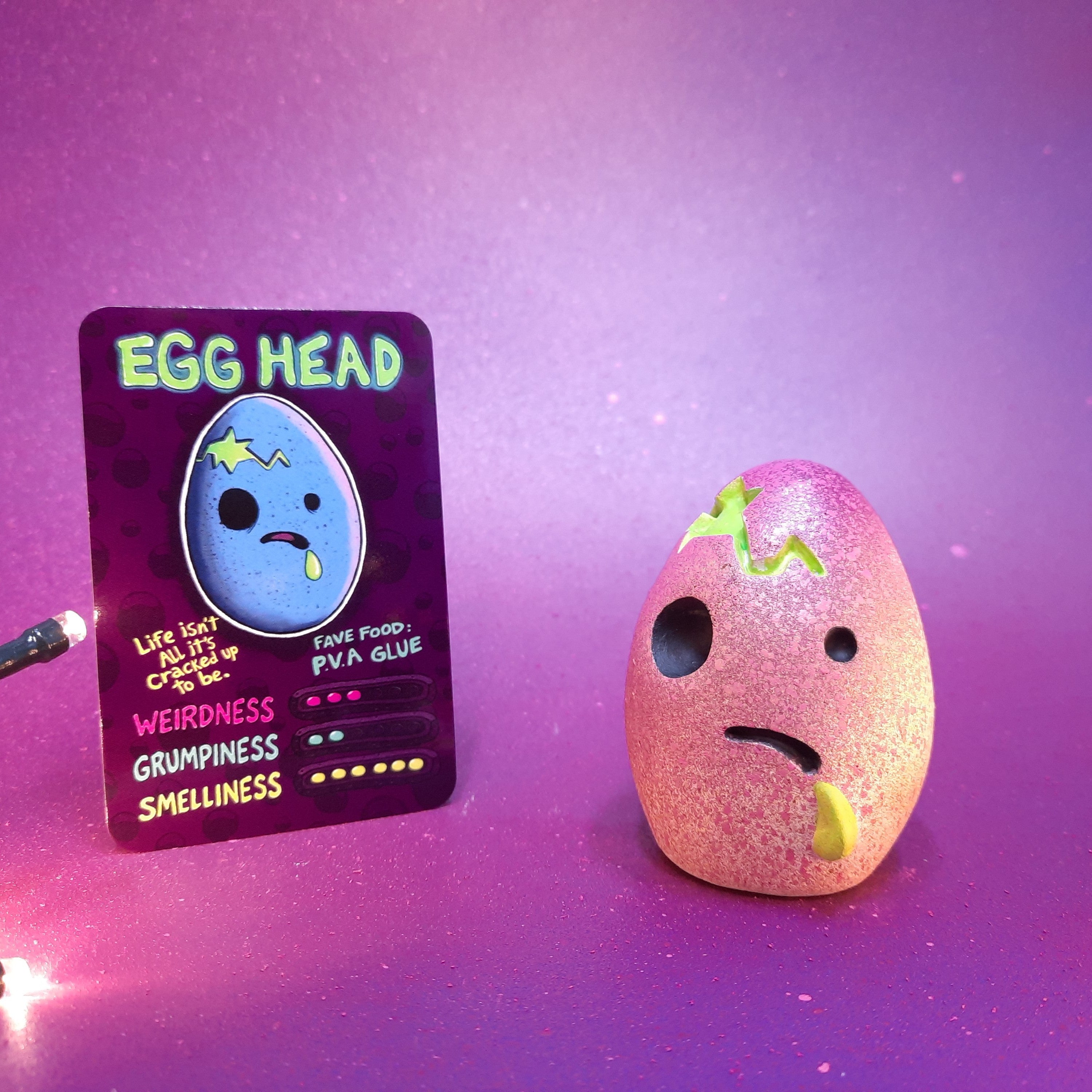 Pink textured 'Egg Head' toy with a matching card on a purple background