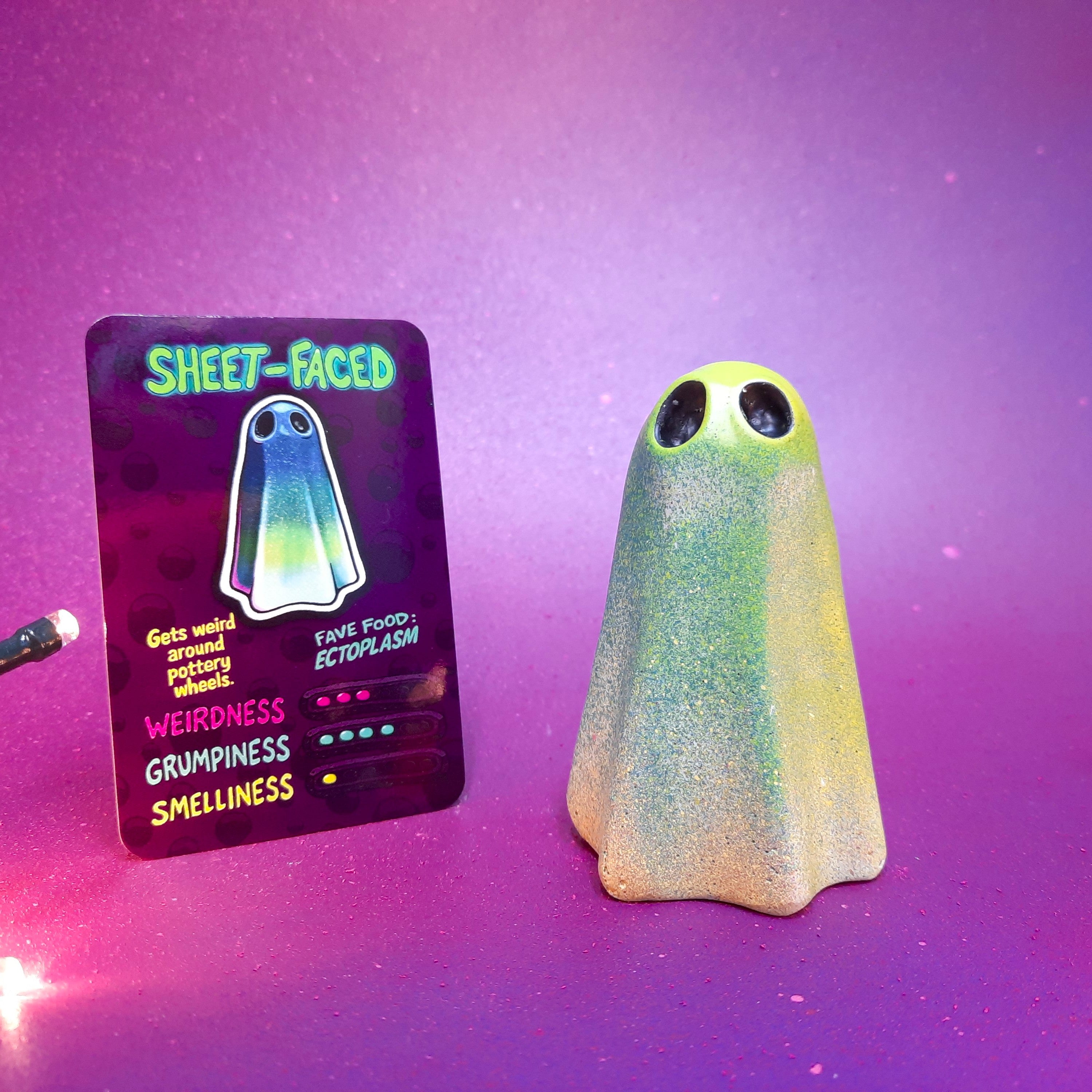 Green ghost-shaped art toy with a card labeled 'Sheet-Faced' on a purple gradient background